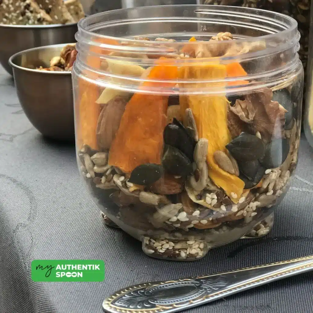 Jar of activated trail mix recipe with dried mango, pumpkin seeds, and sesame seeds on display.