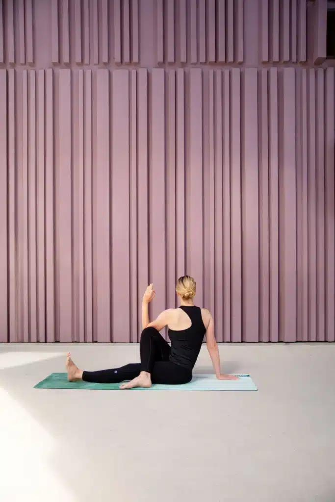 Marine in a seated spinal twist with one leg crossed, practicing Ardha Matsyendrasana outdoors.