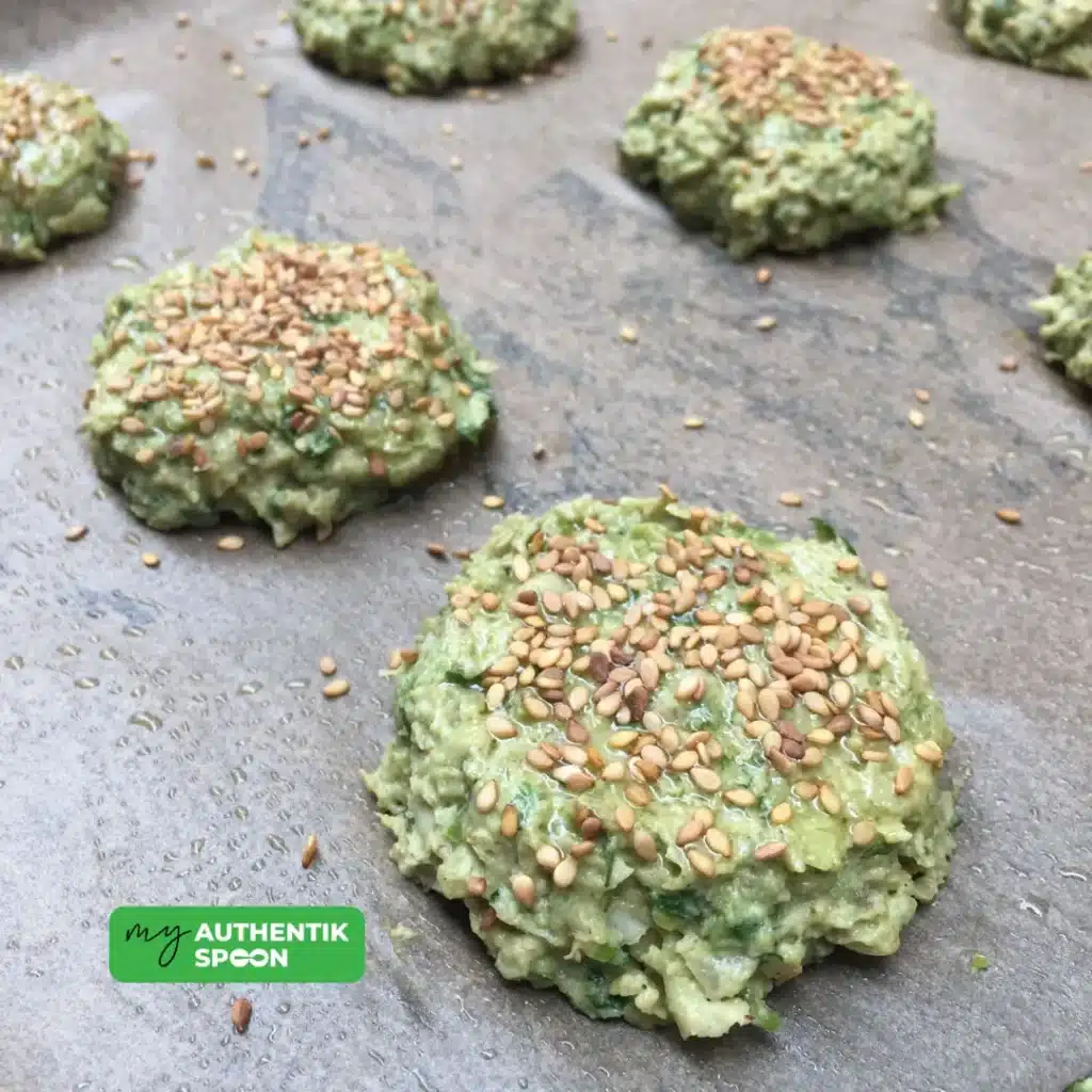 uncooked falafel patties with sesame seeds ready for baking