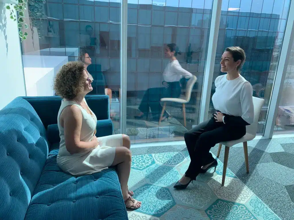 Cathy Jeroudi guiding a woman through a calming sophrology session in a bright, serene room with large windows and natural light.