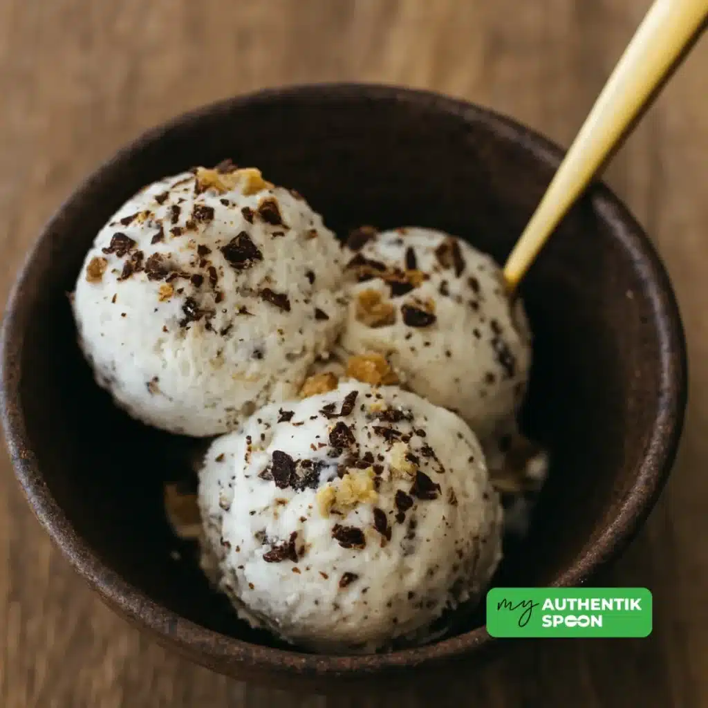 Three scoops of healthy chocolate chip ice cream in a bowl with golden spoon