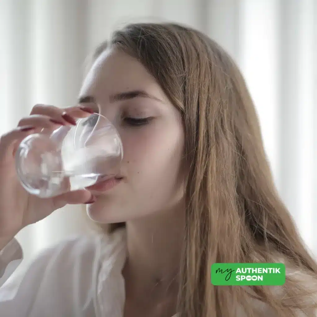 Woman drinking a glass of water, representing clean hydration
