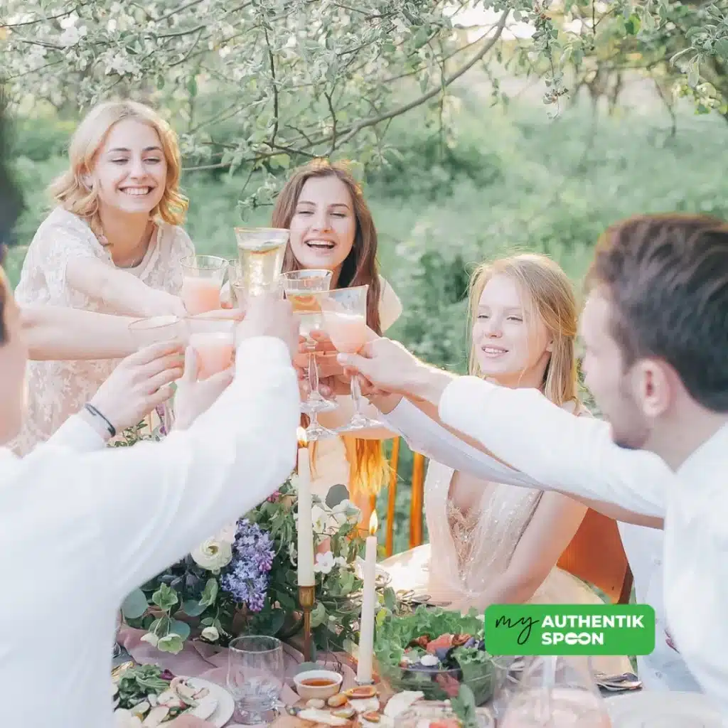 Friends raising glasses at an outdoor summer picnic surrounded by nature