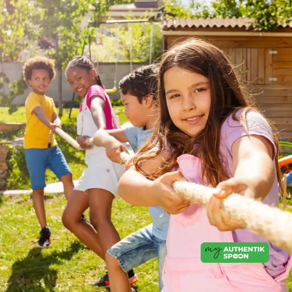 Children playing tug of war outside as part of healthy summer habits to support movement, energy, and social connection