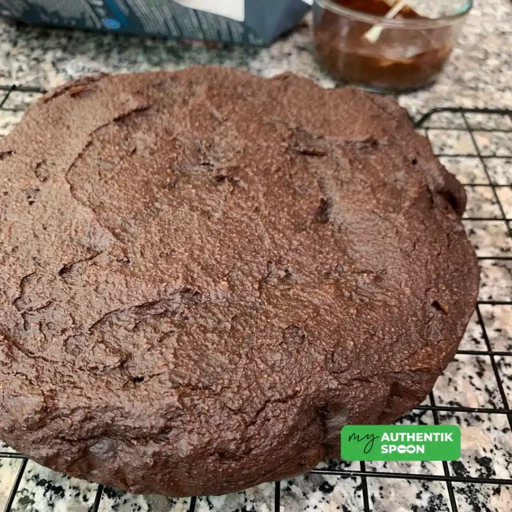 Flourless chocolate date cake fresh from the oven cooling on a rack before topping with dark chocolate glaze