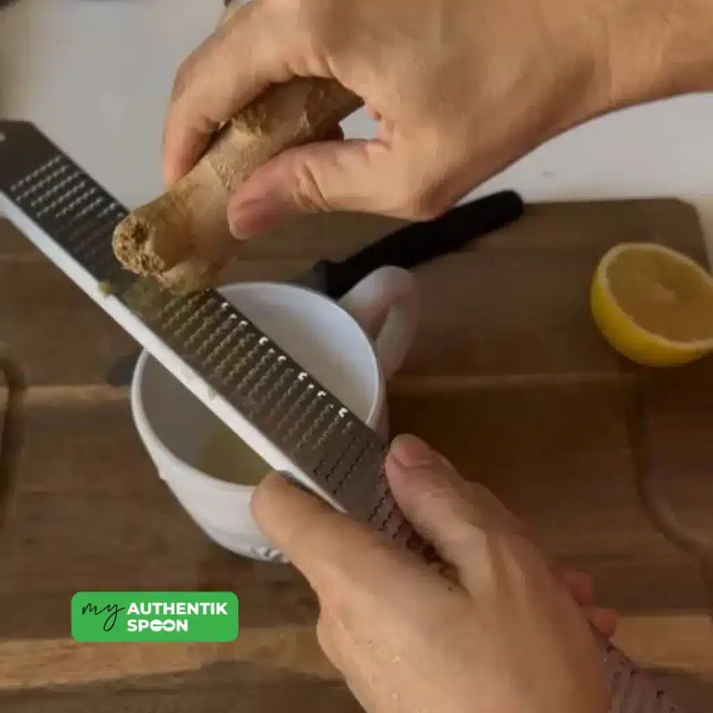 Grating fresh ginger into warm water to make a soothing digestive drink.
