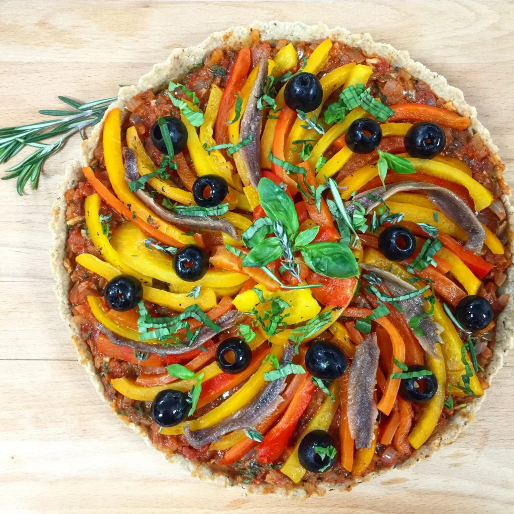 Gluten free pissaladière tart topped with roasted peppers, olives and anchovies