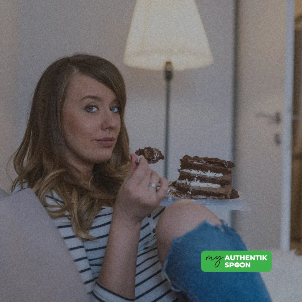 Emotional eating after 35 as a woman eats chocolate cake while seeking comfort during a stressful evening.