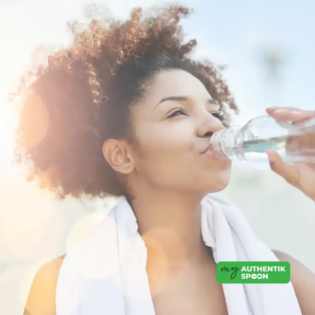 hydration is one of the essential habits for weight loss: Woman drinking water after exercise with sunlight in background, supporting hydration and detox as weight loss habits