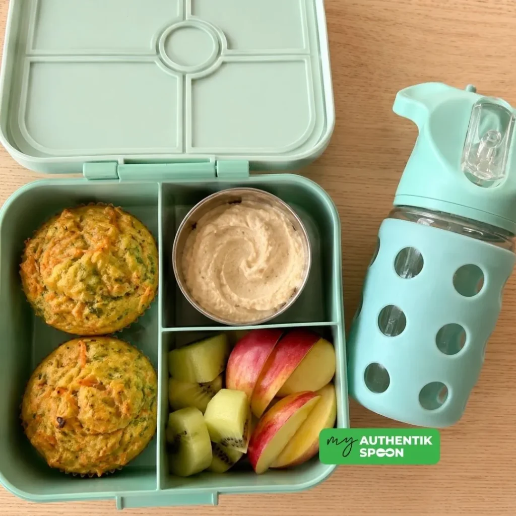 High protein lunchbox packed with muffins, hummus, and fresh fruit